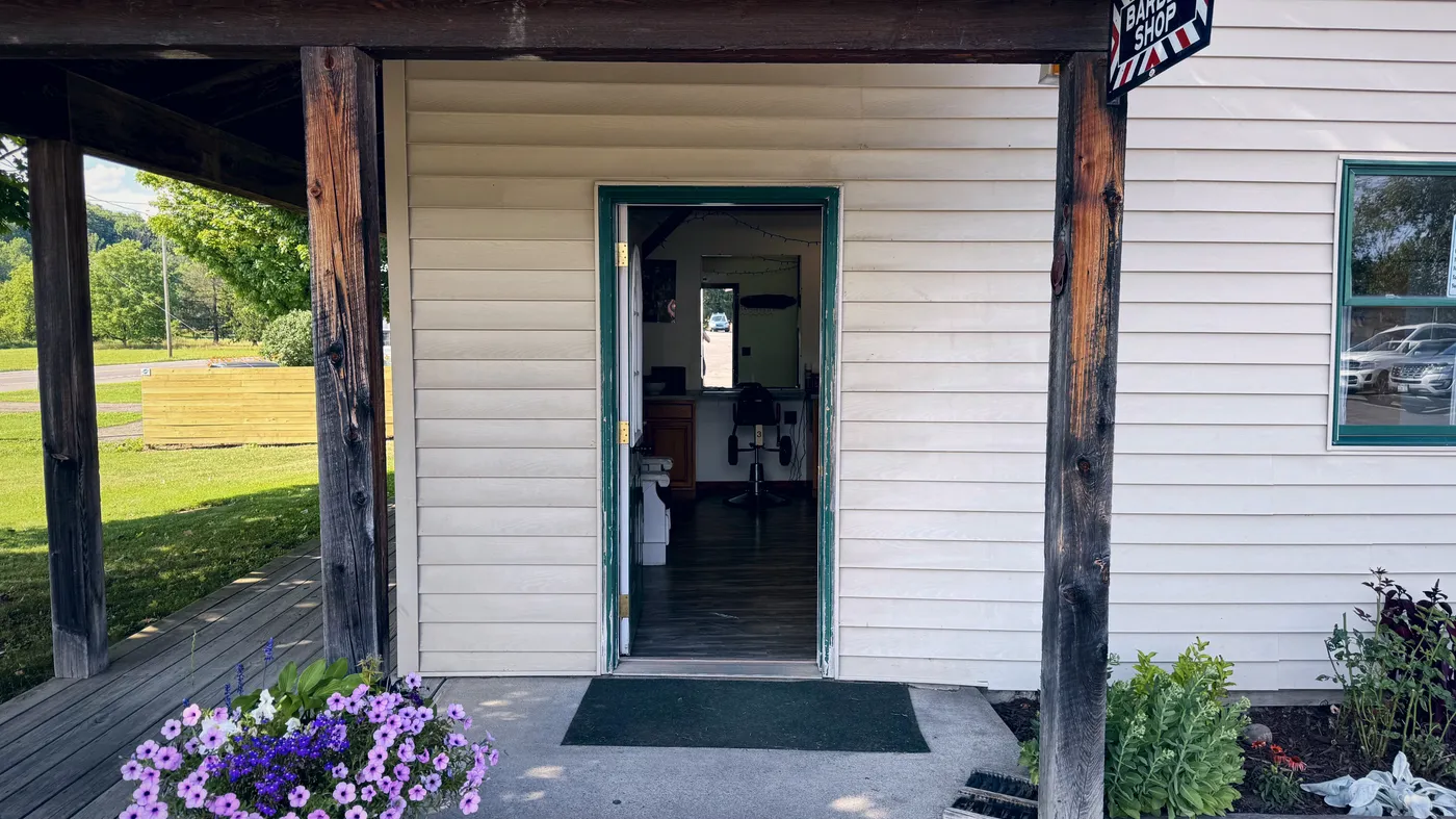 Looking in through the shop's open green door — the barber chair waiting inside.
