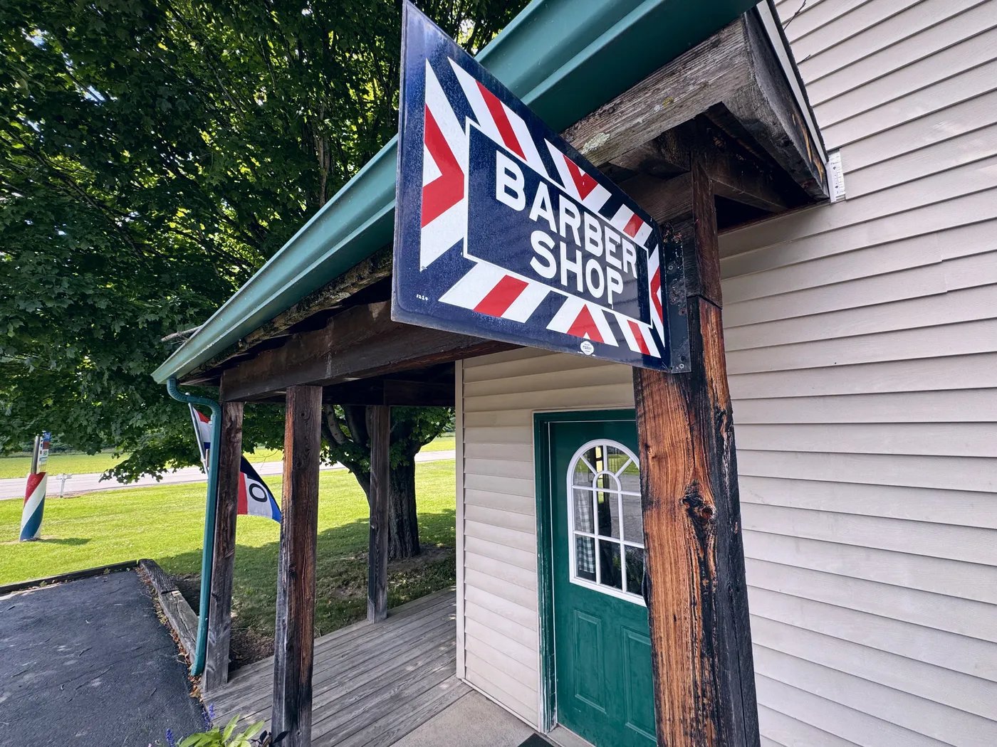 The hanging “Barber Shop” sign under the porch roof.